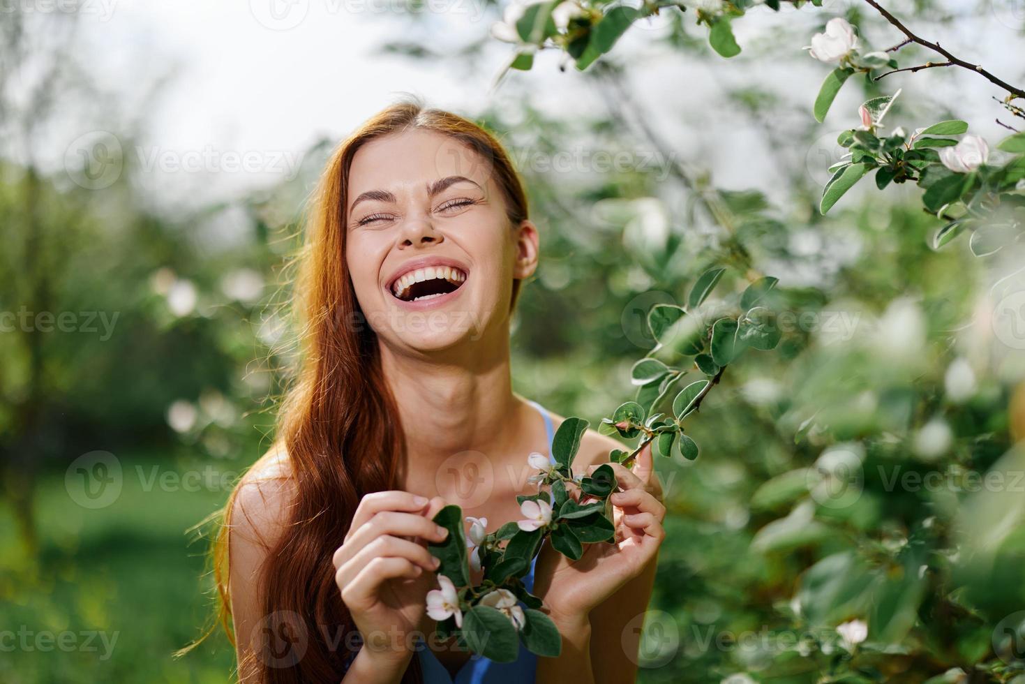 Woman portrait smiling beautifully with teeth and looking into the camera in spring happiness in nature against a green tree, safety from allergies and insects photo