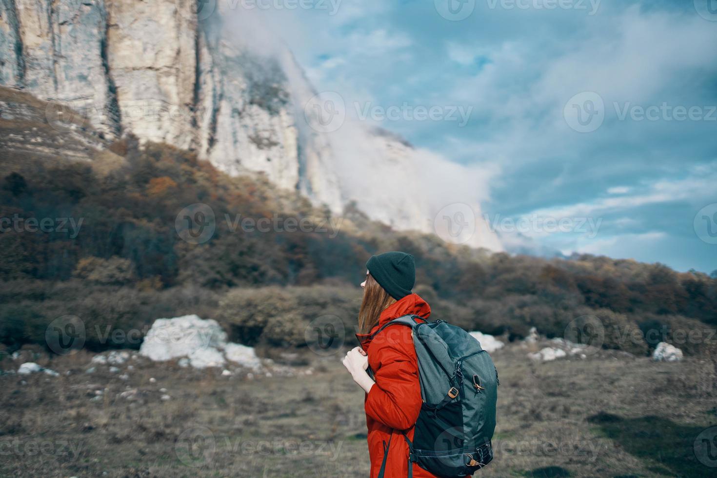 travel of a woman in a jacket with a backpack hat on his head blue sky and high mountains photo
