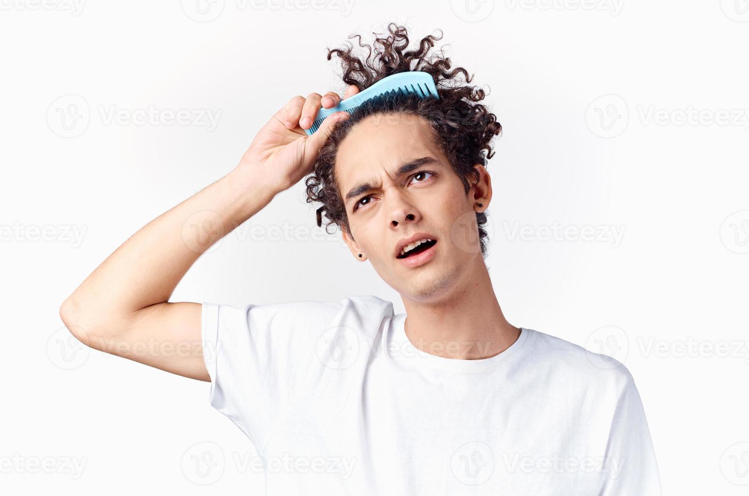 curly guy stuck comb in his hair emotions light background photo