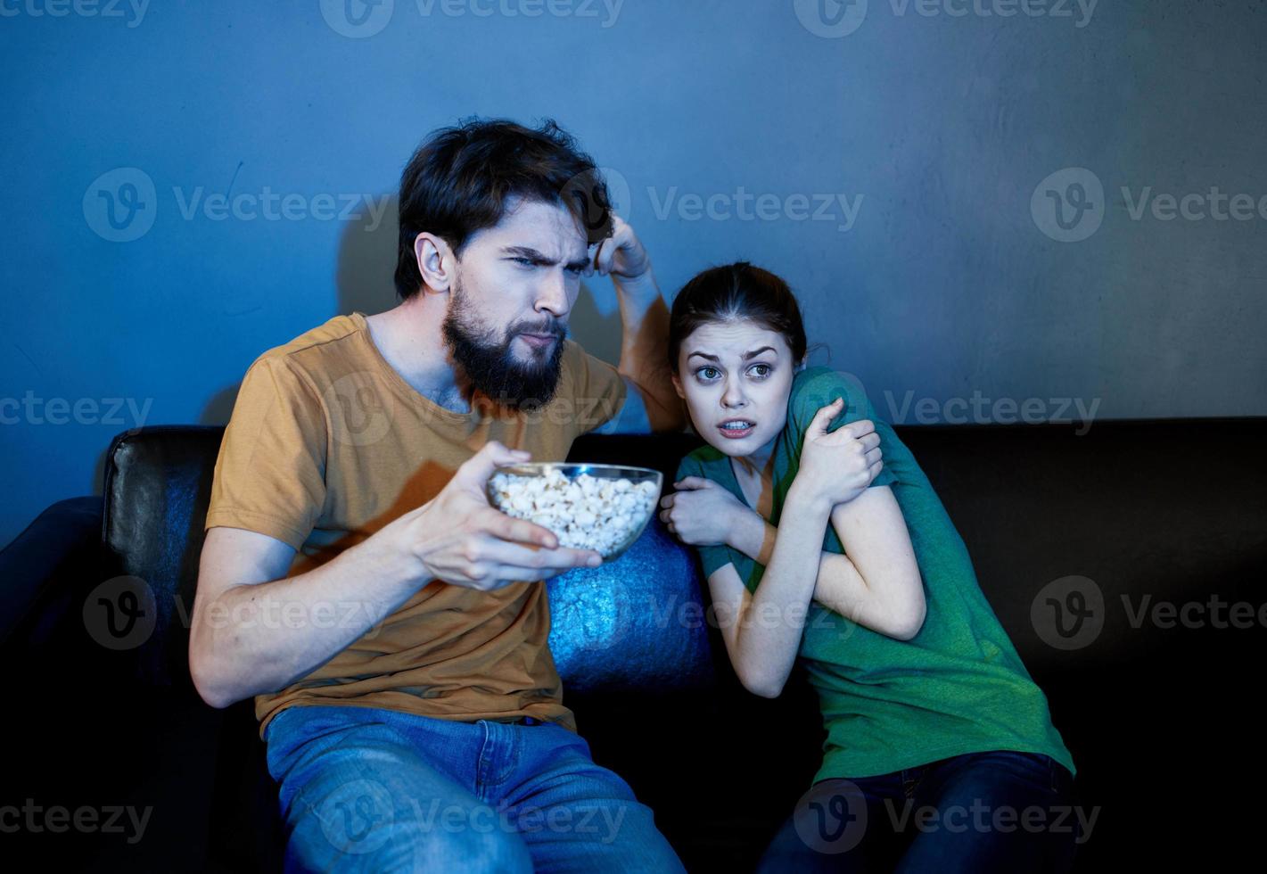 A married couple on the couch watching TV and popcorn indoors photo