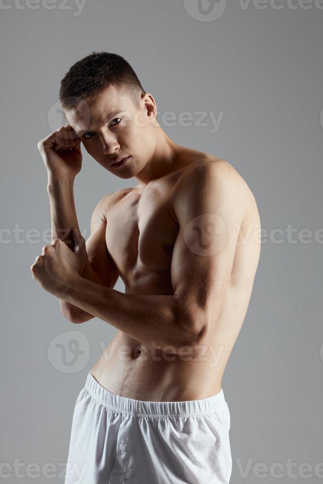 athlete with pumped-up torso gesturing with hands on gray background cropped view photo