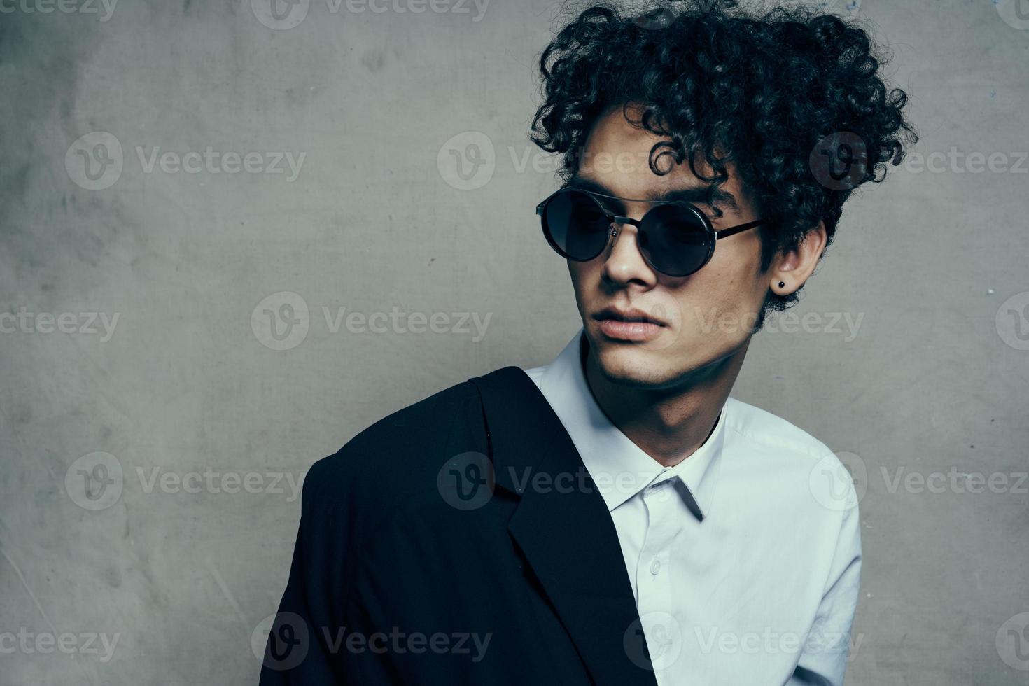 fashionable curly haired brunet guy in a shirt with glasses and a jacket on his shoulder photo