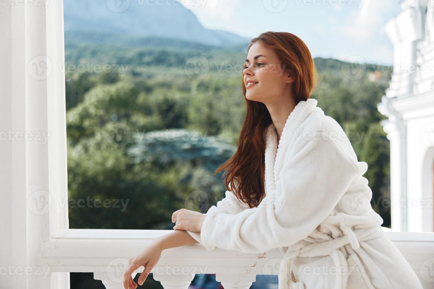 woman in a white robe on the balcony bit on green nature Relaxation concept photo