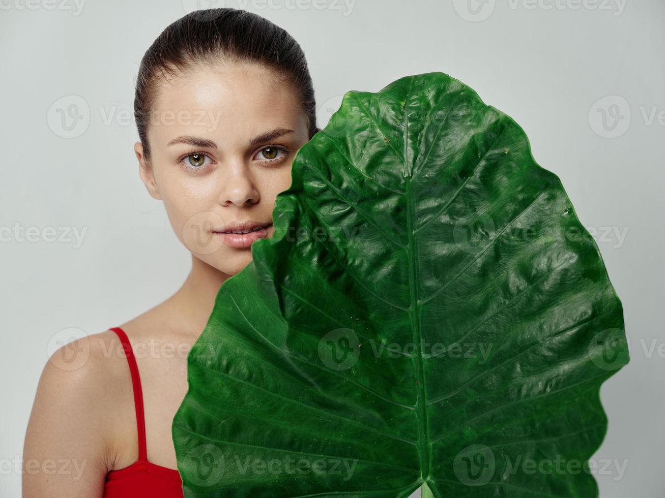 woman in red t-shirt on light background with green leaf of palm tree photo