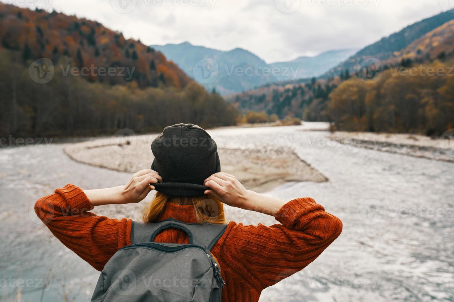 mujer viajero en vacaciones en el montañas en naturaleza cerca el río sostener manos detrás su cabeza foto