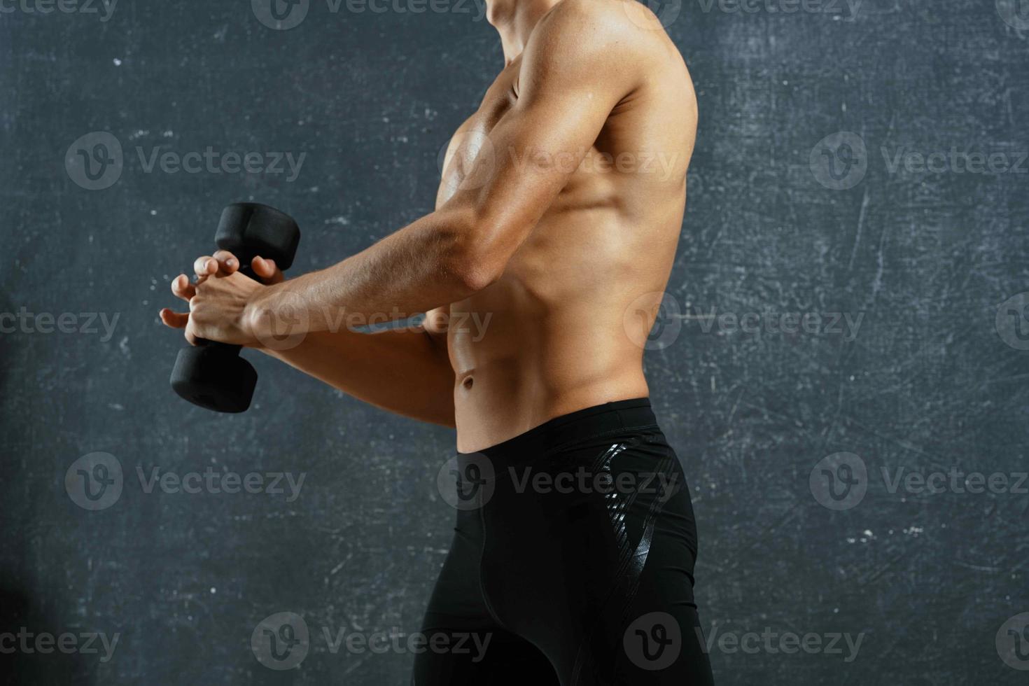 sporty man with a pumped up body workout exercises dark background photo