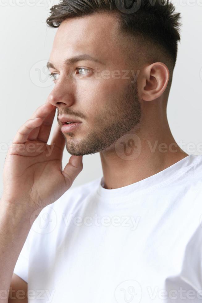 Portrait shot of handsome pensive romantic serious tanned man guy in basic t-shirt looks aside posing on white background. Fashion Style New Collection Offer. Copy space for ad. Model snap photo