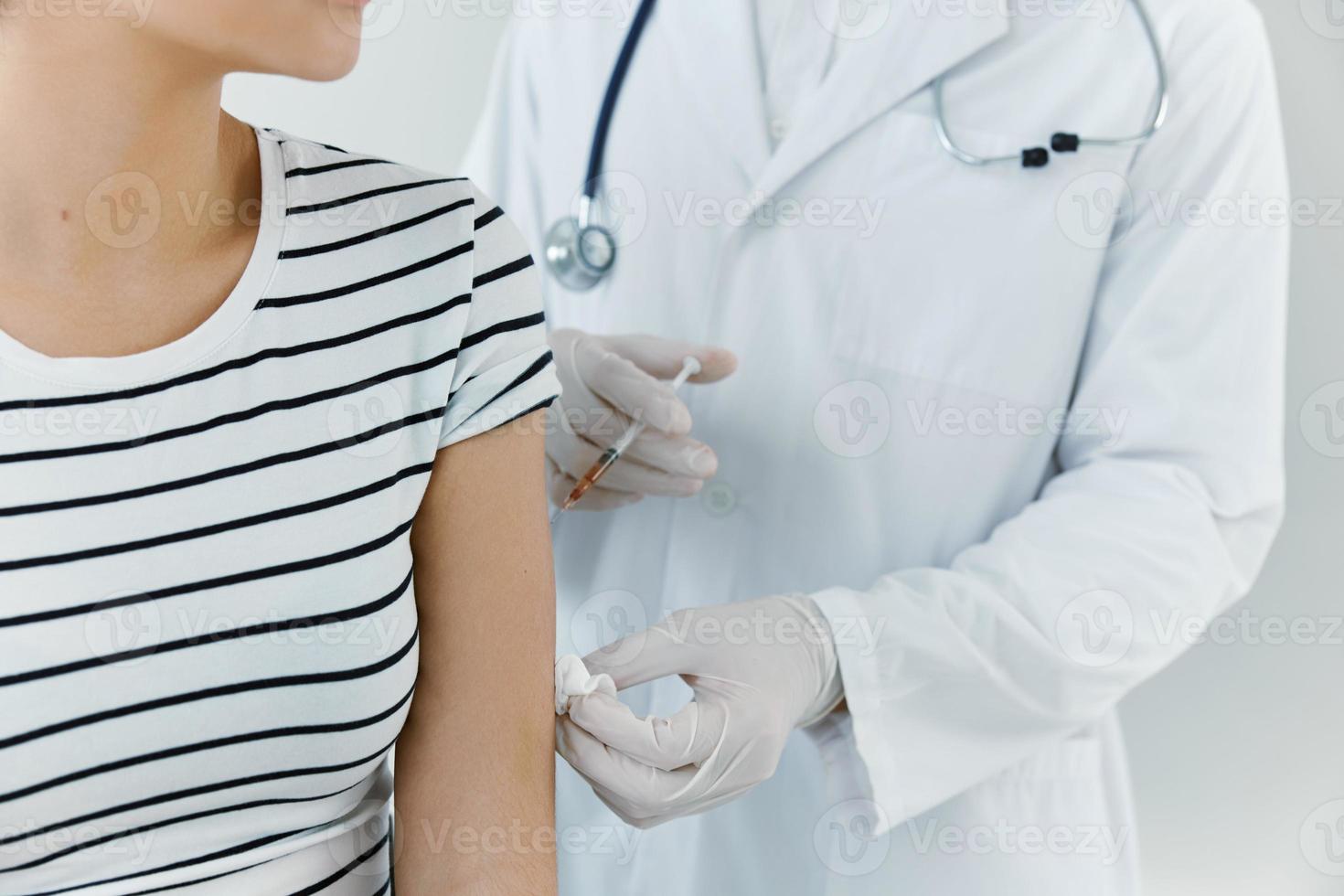 médico con médico guantes inyecta el vacuna dentro el del paciente mano de cerca foto