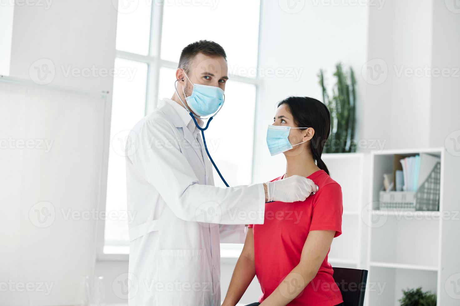 doctor examines woman in medical mask red t-shirt stethoscope photo