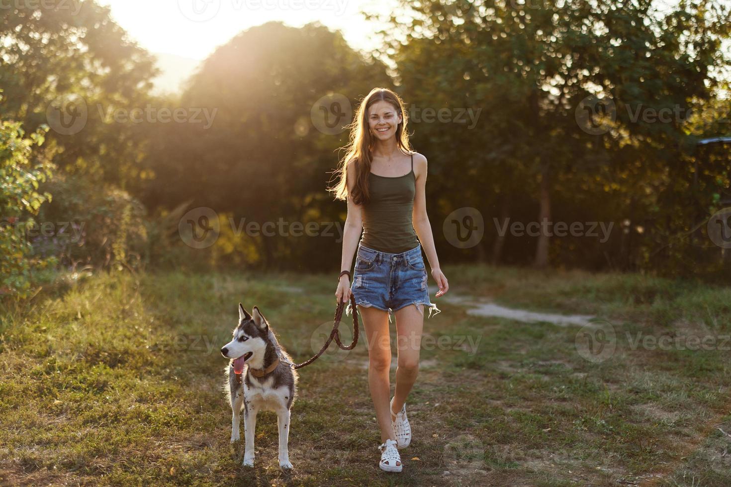 Woman and her husky dog walking happily on the grass in the park smile with teeth in the fall walk with her pet, travel with a dog friend photo