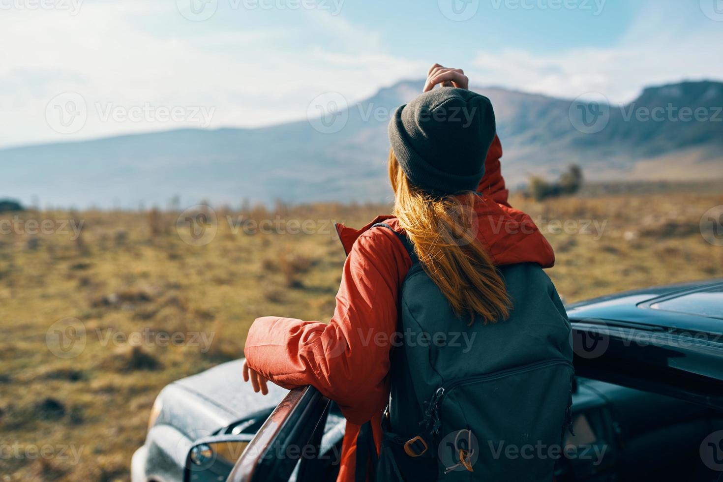 traveler in a hat with a backpack near the car door in nature photo