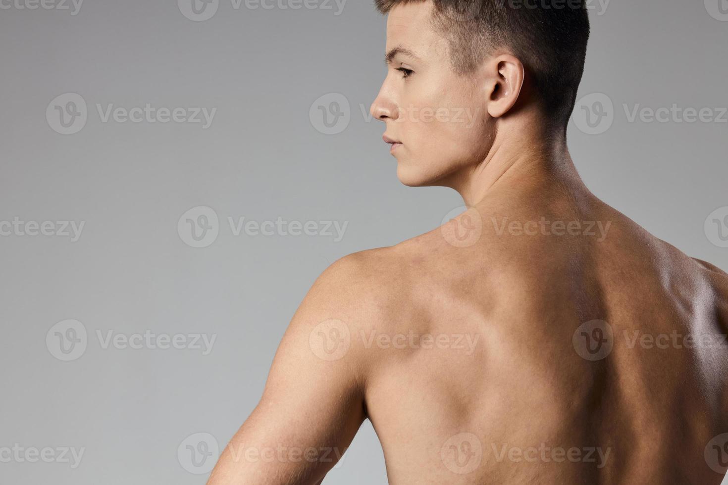 strong athlete with bulging arm muscles naked back back view gray background photo