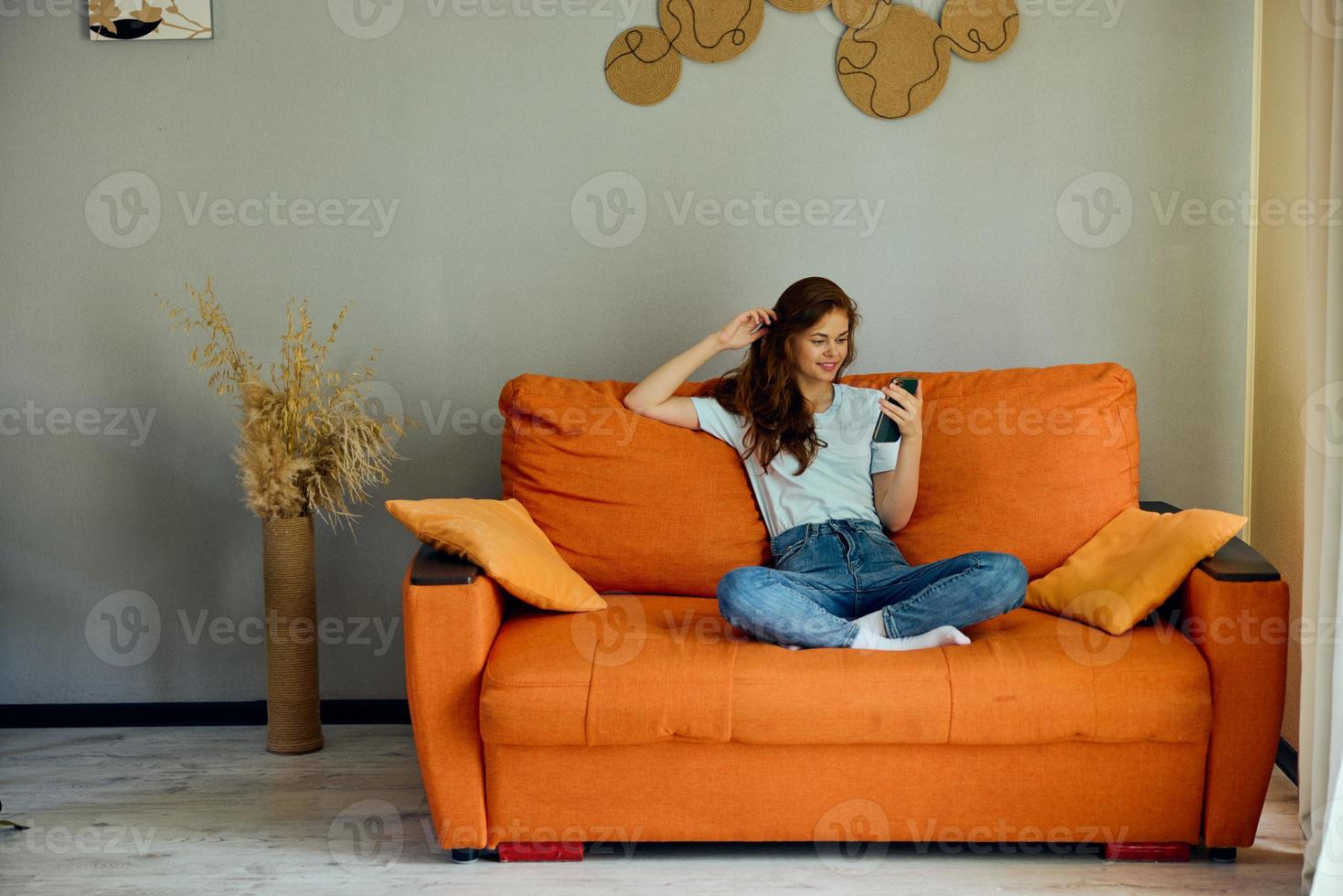 pretty woman with a phone in his hands on the couch technologies photo