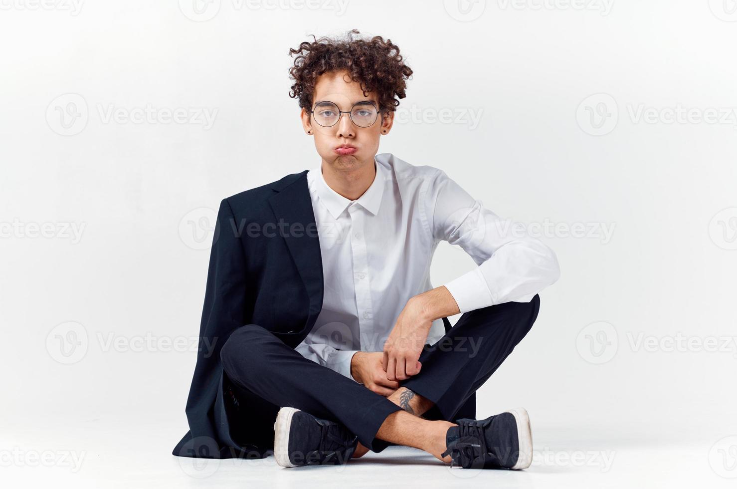 stylish young man with curly hair and in a classic suit on a light background photo