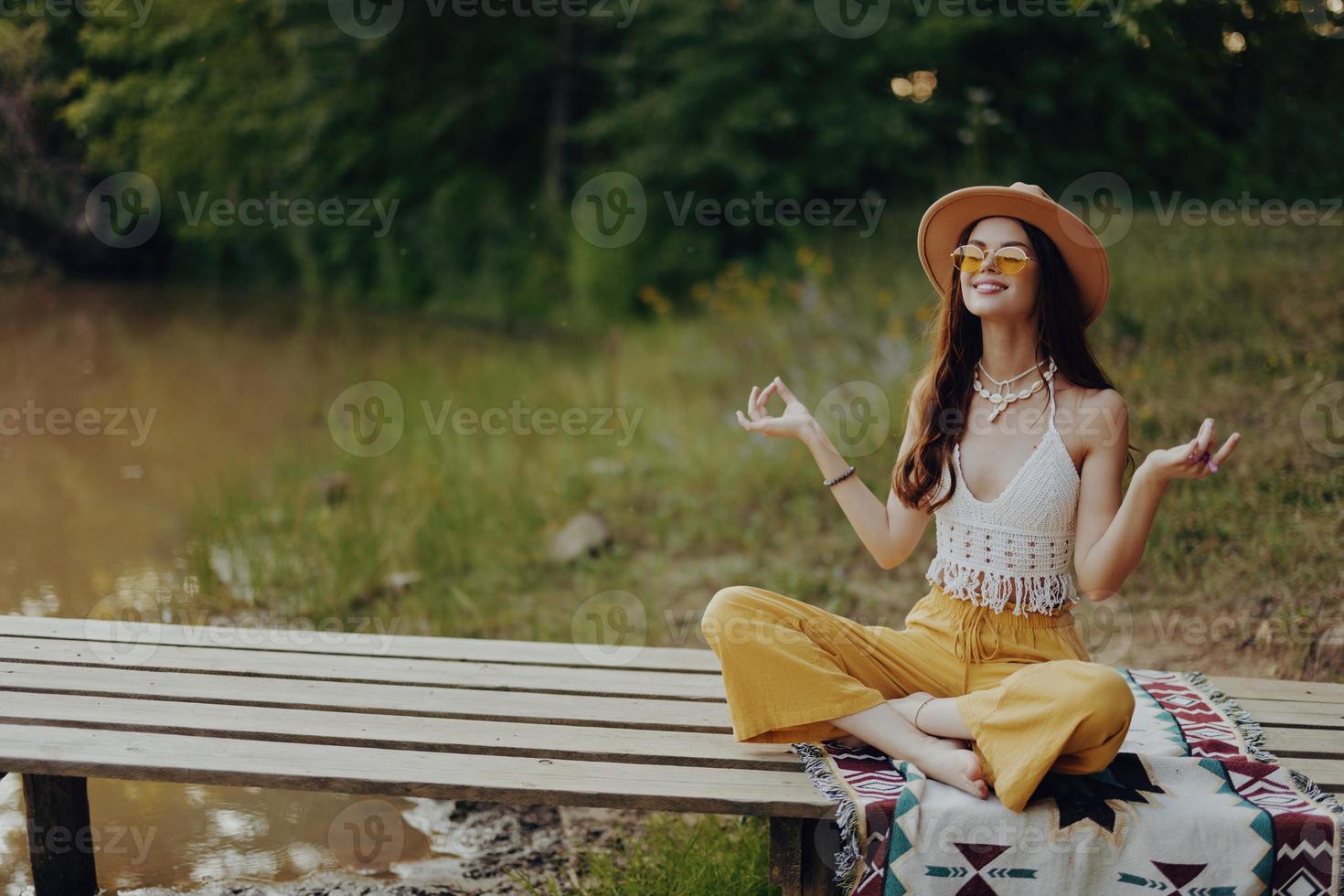 A hippie woman meditating in nature in the lotus position in the sunset light photo