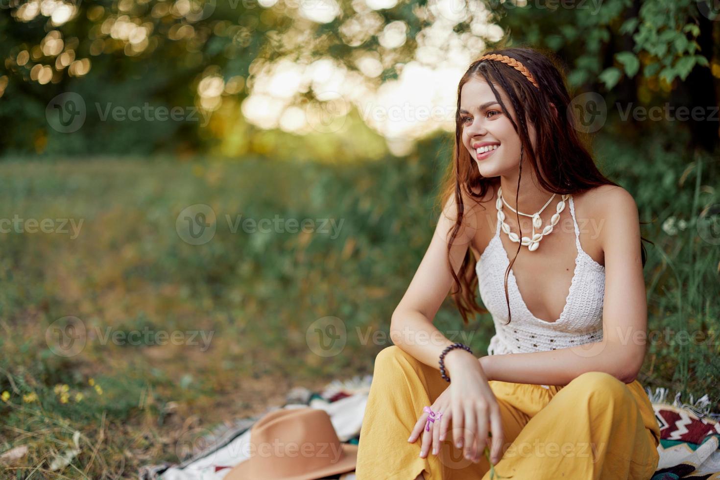 niña vestido como un hippie eco relajante en el parque, sentado en un cobija en el atardecer, relajado estilo de vida foto