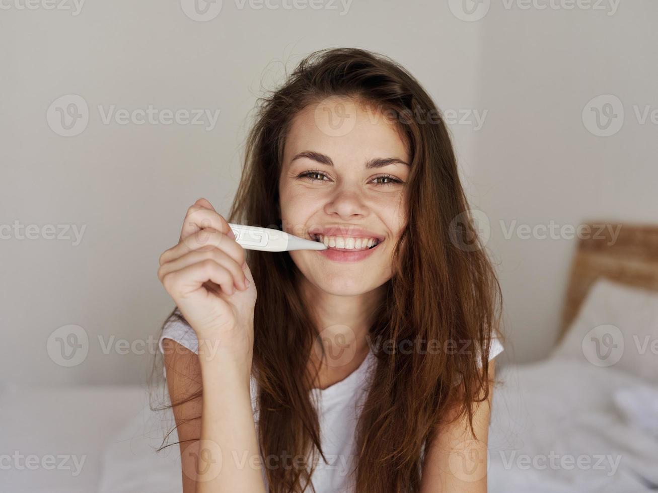 sonriente mujer participación termómetro en dormitorio boca comprobación temperatura foto