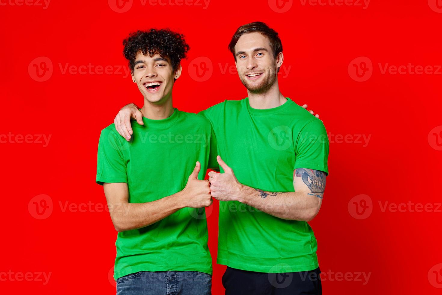 two men hugging in green T-shirts on a red background photo