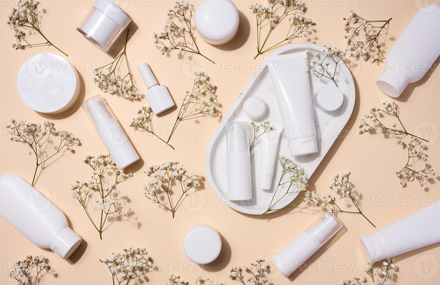 blanco el plastico tubos, frascos, y Gypsophila ramas en un beige fondo, contenedores para cosmético cremas y geles, publicidad y marca promoción, parte superior ver foto