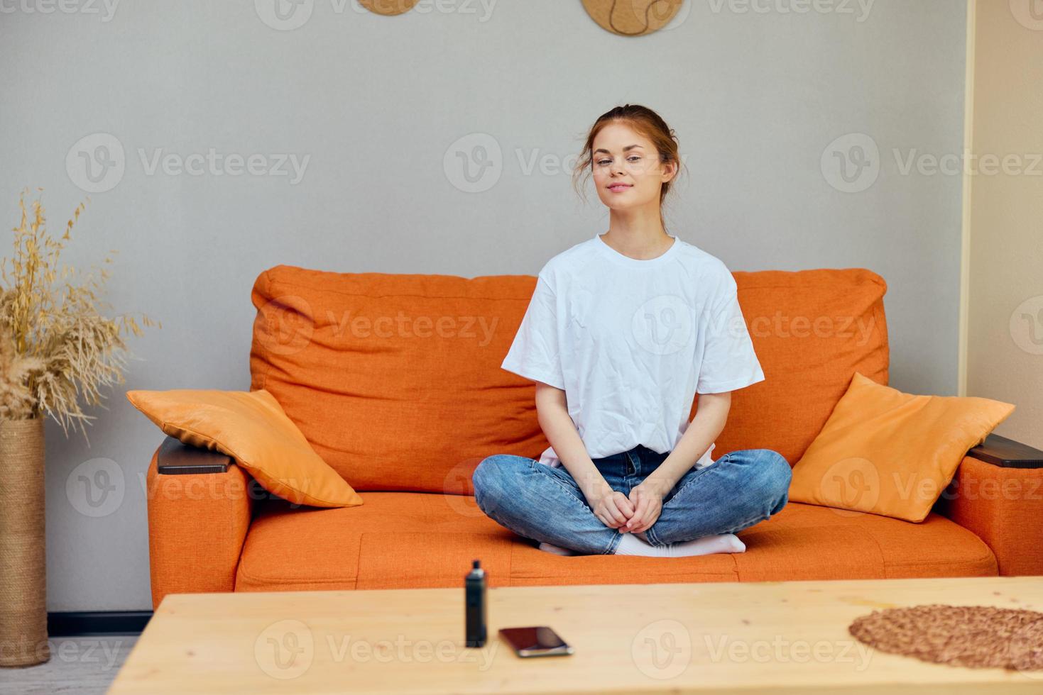 woman sitting on the couch at home near the table with a phone and vape photo