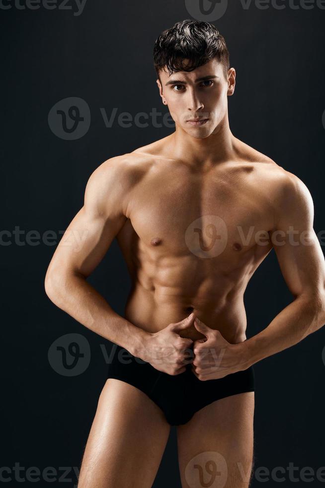 handsome man with muscular body in dark in shorts posing isolated background photo