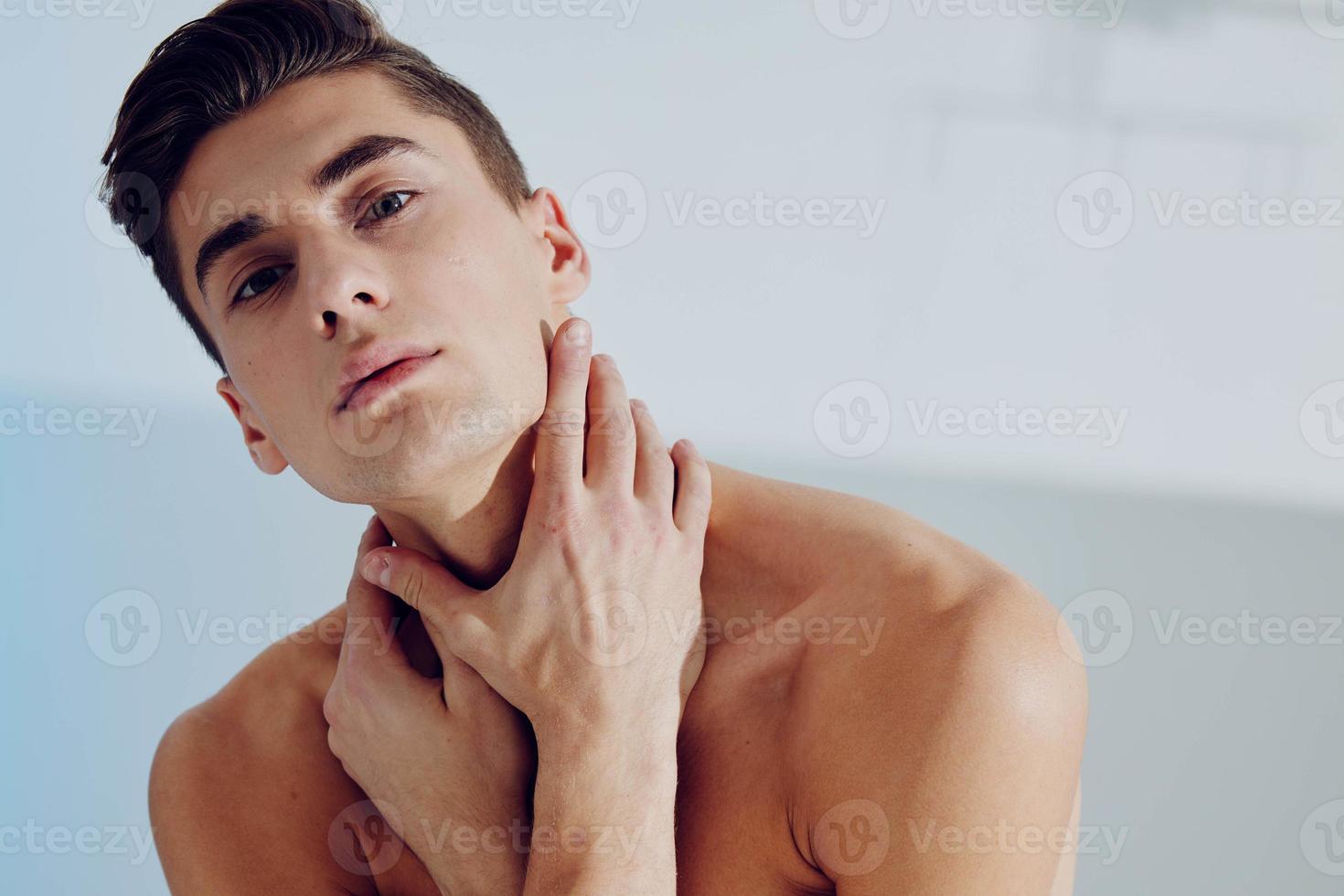 Portrait of a young man who touches his neck with a naked torso photo