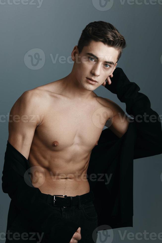 A guy in a black jacket holds his hand above his head and a naked torso photo