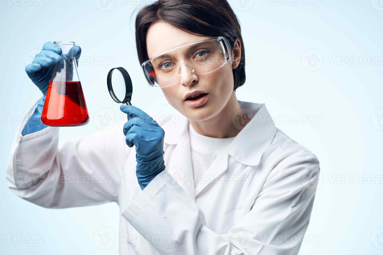 woman scientist looking through a magnifying glass at a chemical solution work biotechnology photo