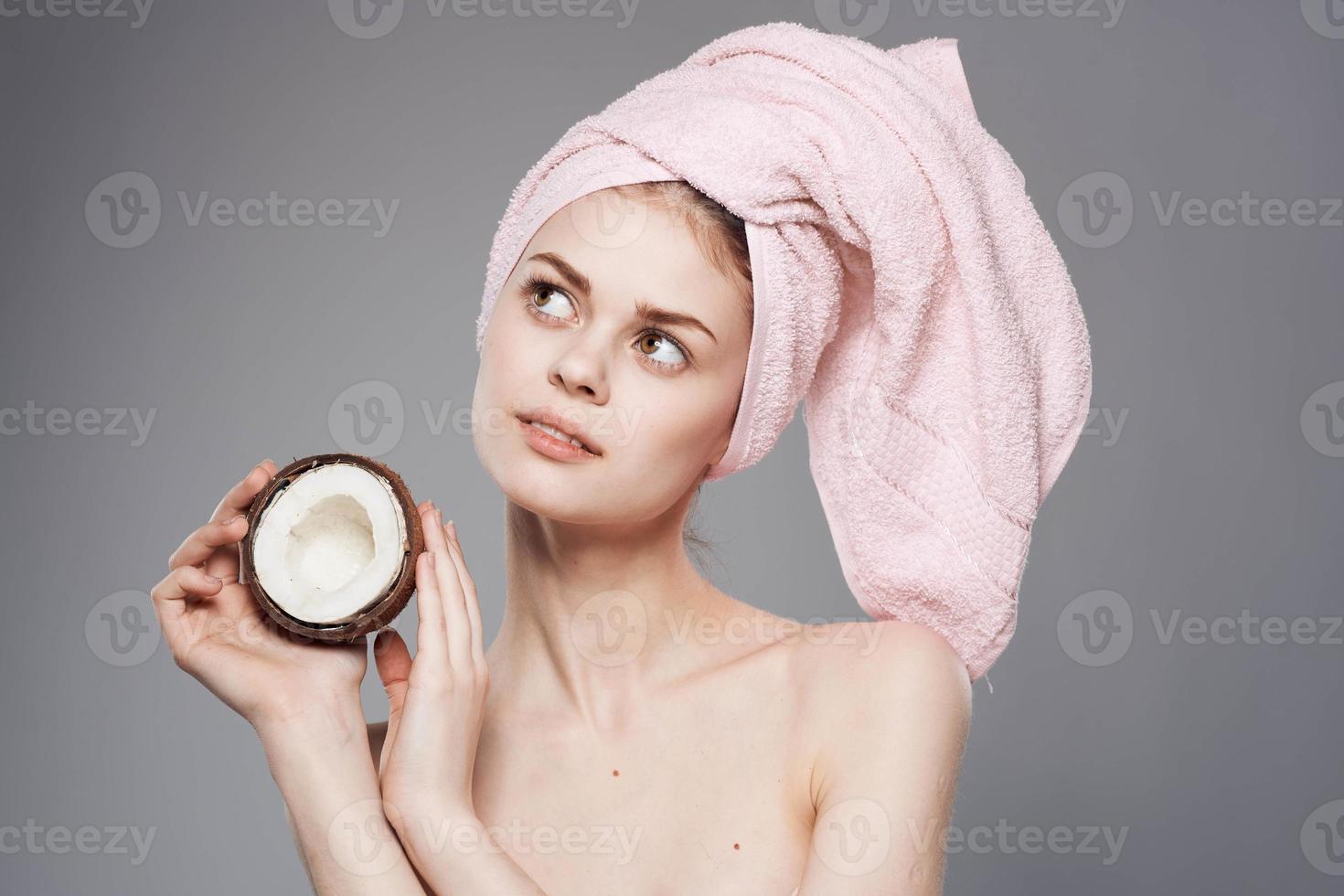 mujer con desnudo espalda con un Coco en su manos limpiar piel exótico natural productos cosméticos gris antecedentes foto