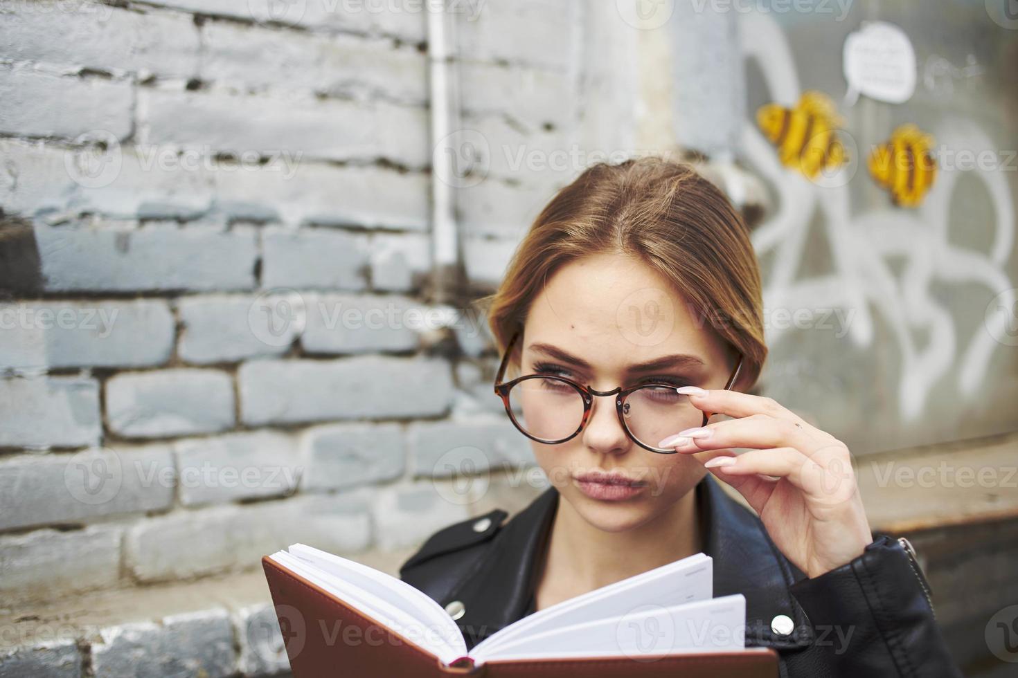 Woman in a black jacket with a notebook in her hands near a brick building cropped view photo