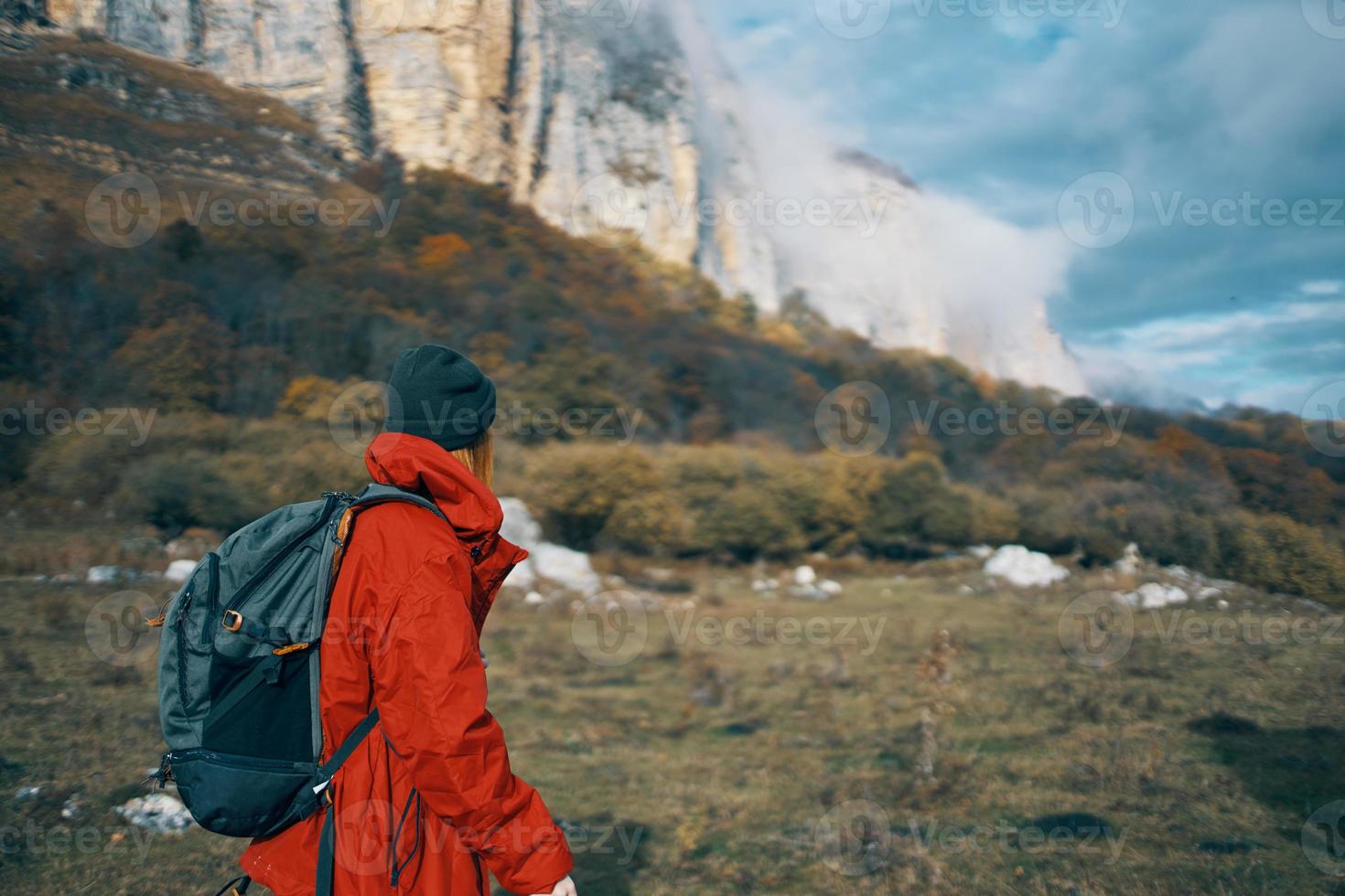 woman in jackets caps with a backpack on her back walks in the fall in the mountains and in nature photo