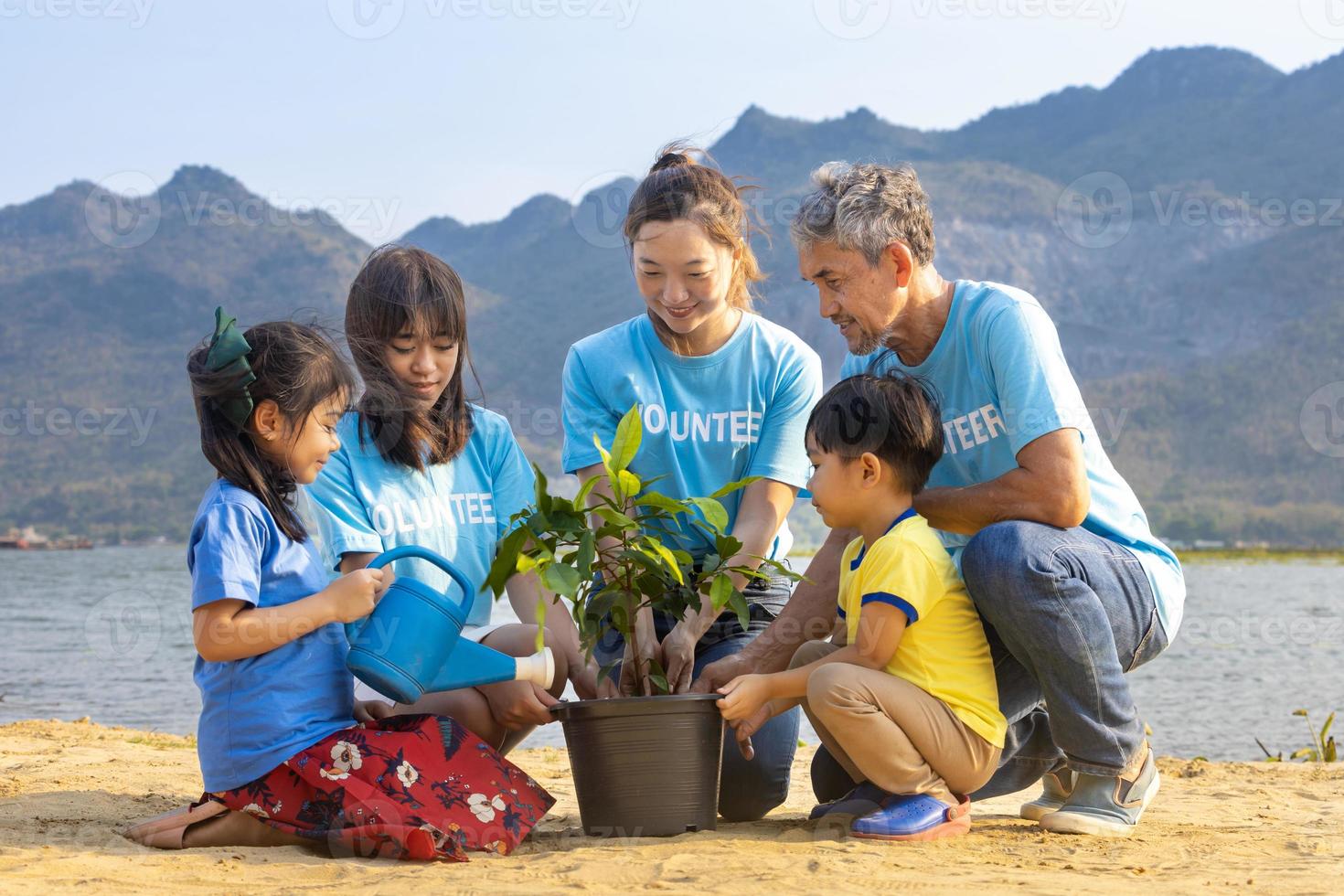 Team of volunteer worker group teaching children to planting tree in charitable social work on forest rewilding NGO work for fighting climate change and global warming in the coastline habitat photo