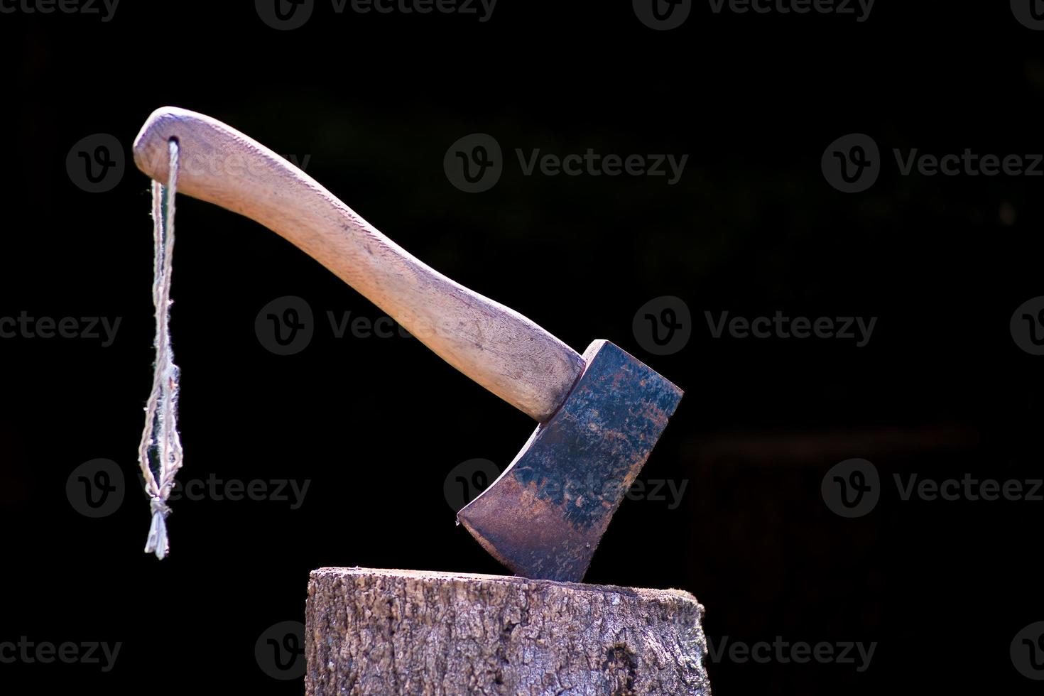 Rusty iron ax attached to a tree log. On a black background. photo