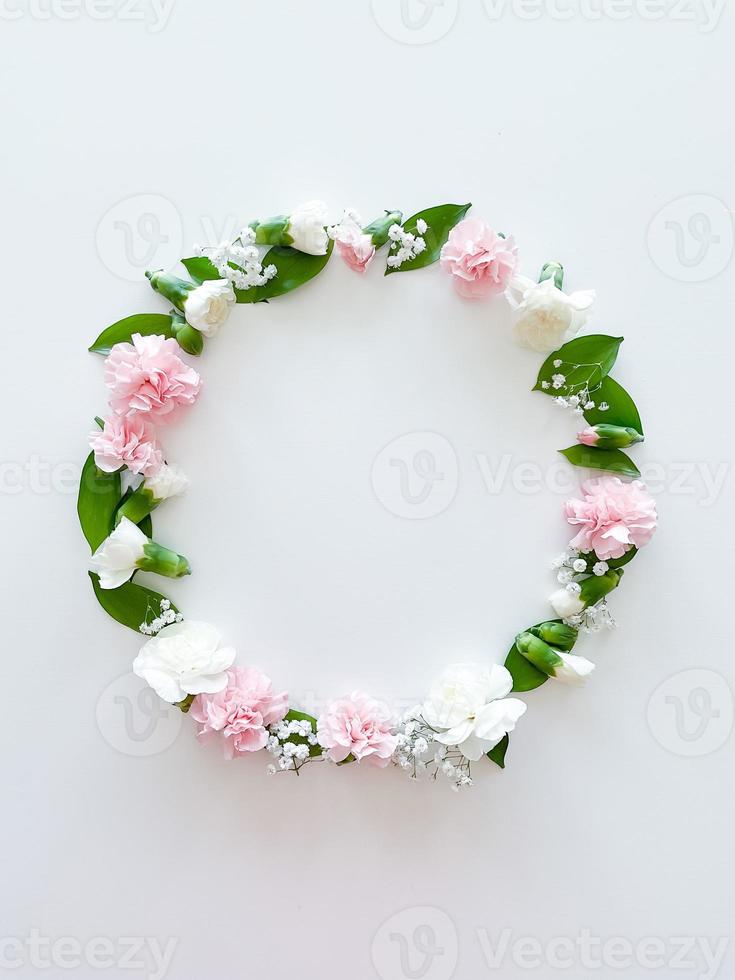 Round frame of pink and white carnations, leaves photo