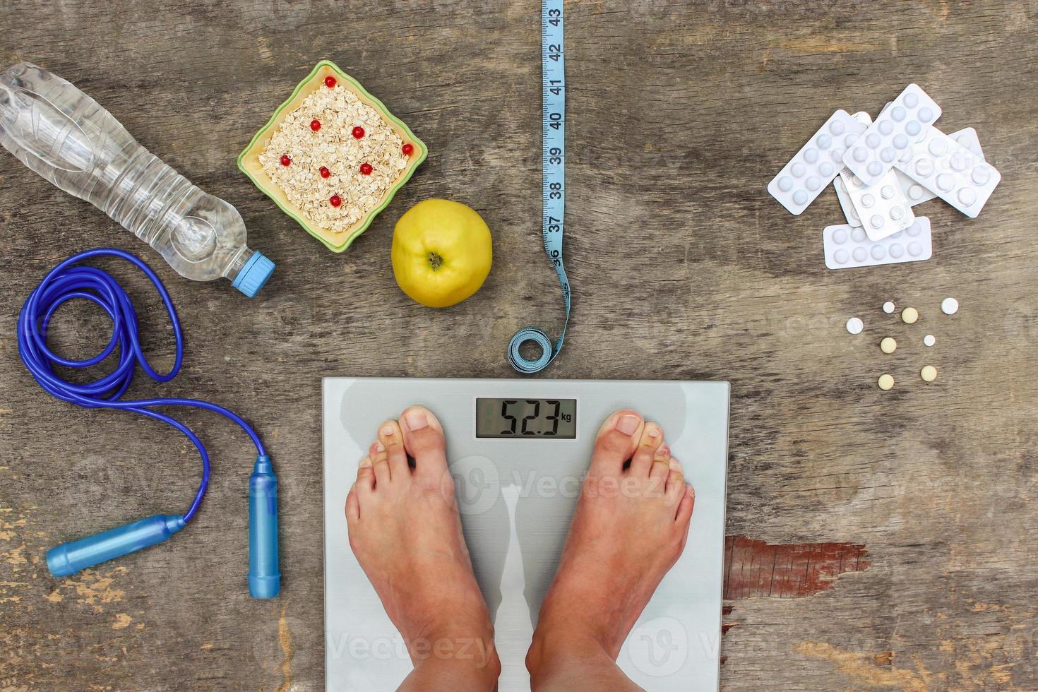 Concept of different ways to lose weight. Scales, tape measure, apple, oatmeal, jump rope, water, medicine. photo