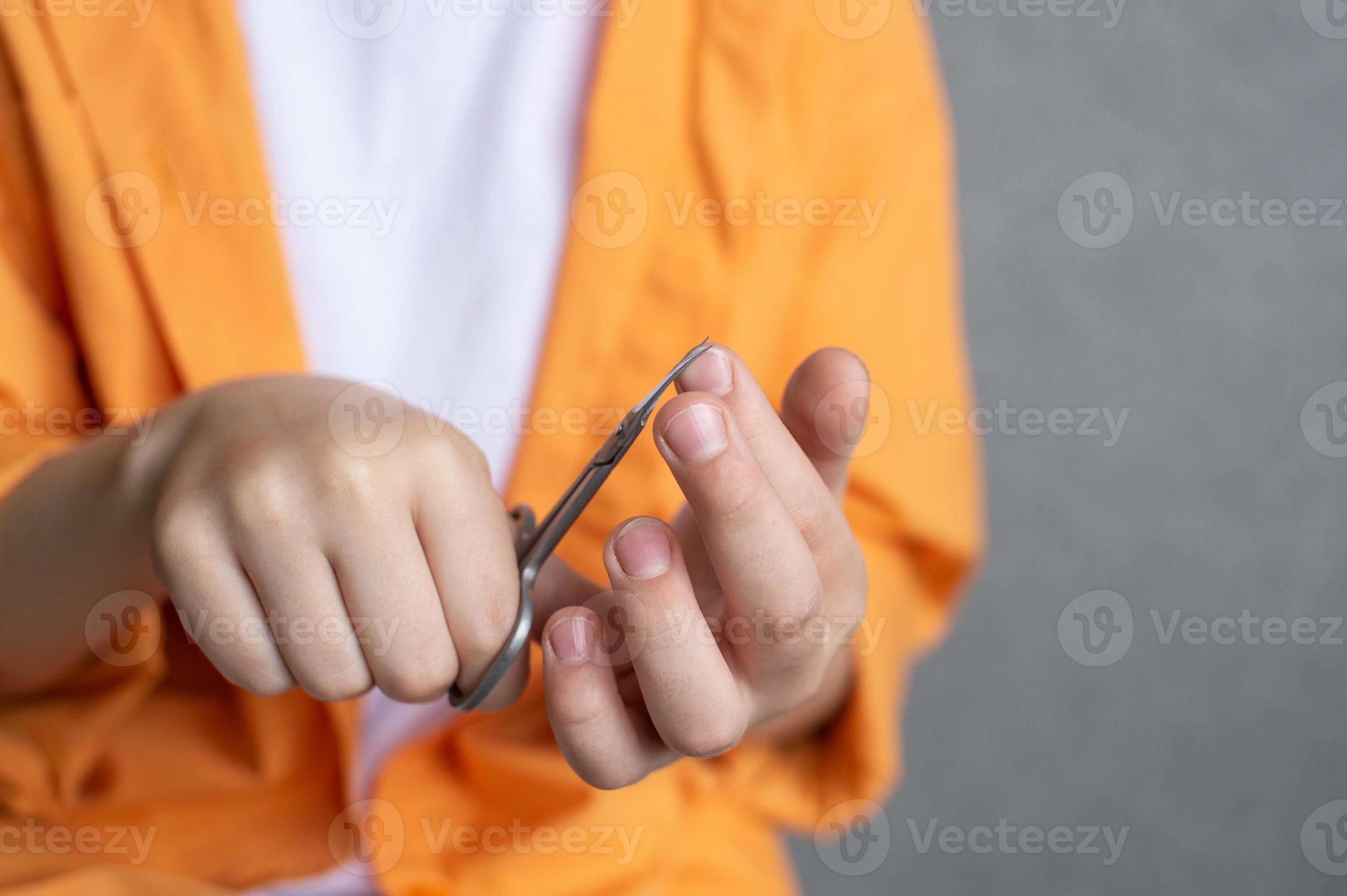 Manicure scissors in the hands of a child cut nails 22029503 Stock