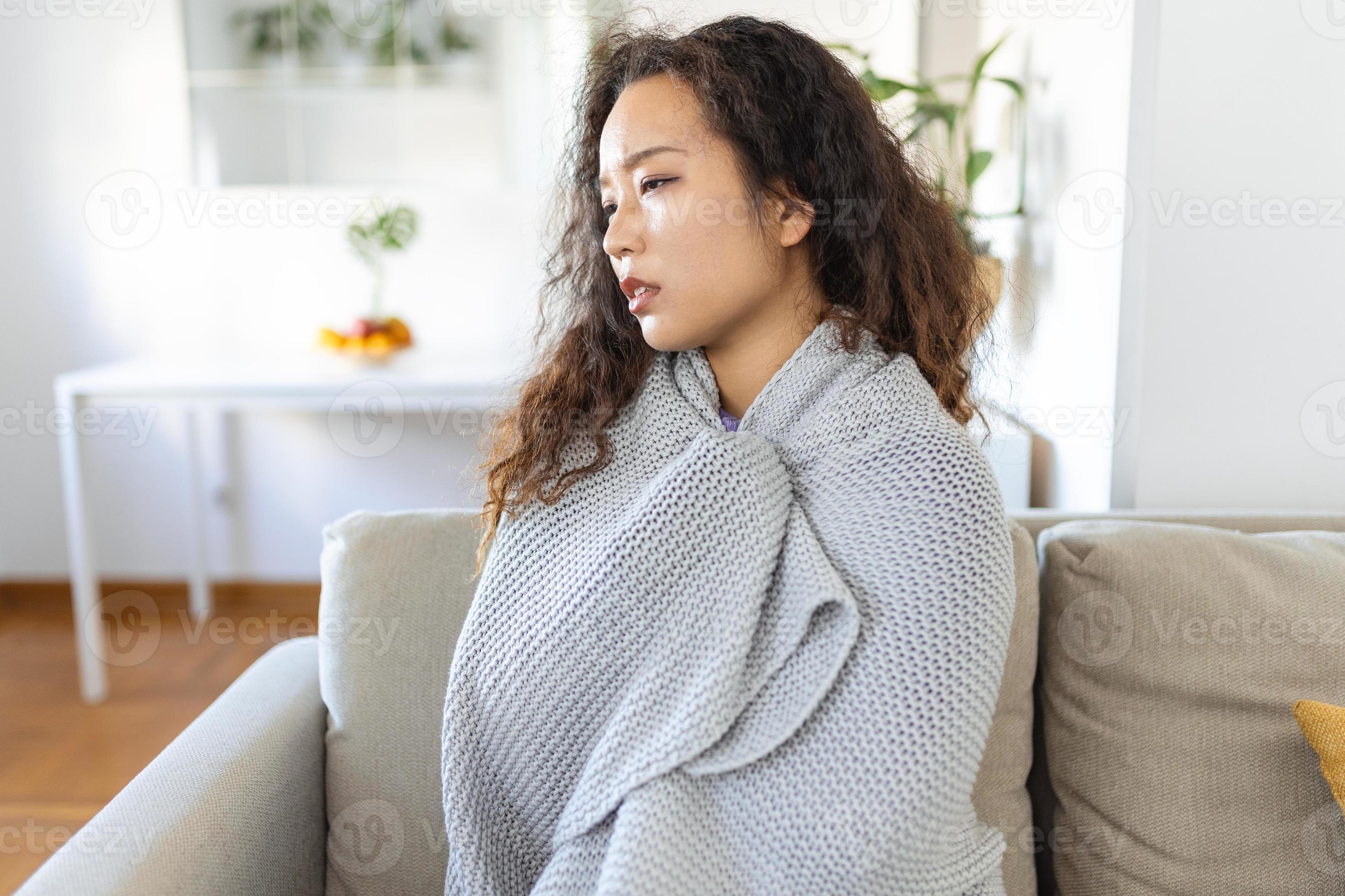 Sick young Asian woman feeling cold covered with blanket sit on bed