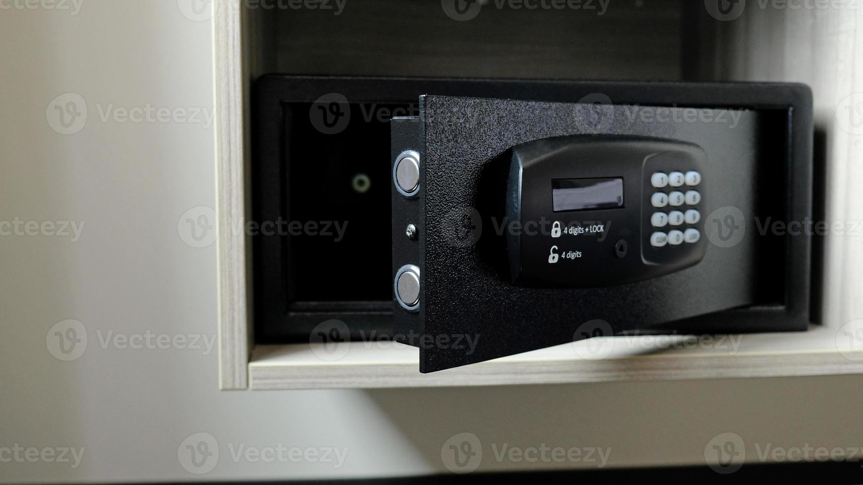 Metal safe box in the closet. Small narrow safe for keeping money or valuables in the hotel. Open safe door with buttons for entering a password. Compact strongbox inside cabinet. Empty safe. photo