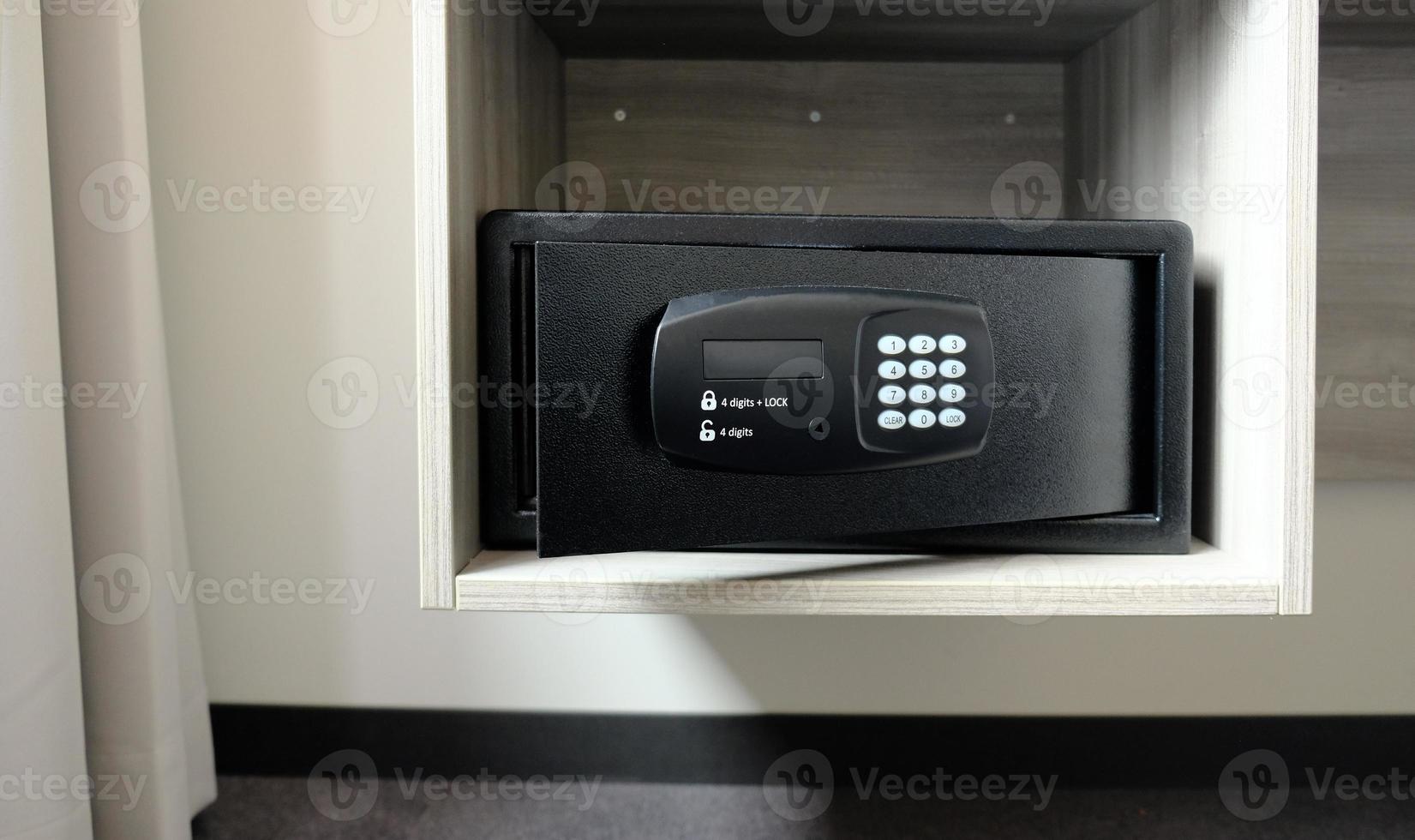 Metal safe box in the closet. Small narrow safe for keeping money or valuables in the hotel. Open safe door with buttons for entering a password. Compact strongbox inside cabinet. Empty safe. photo