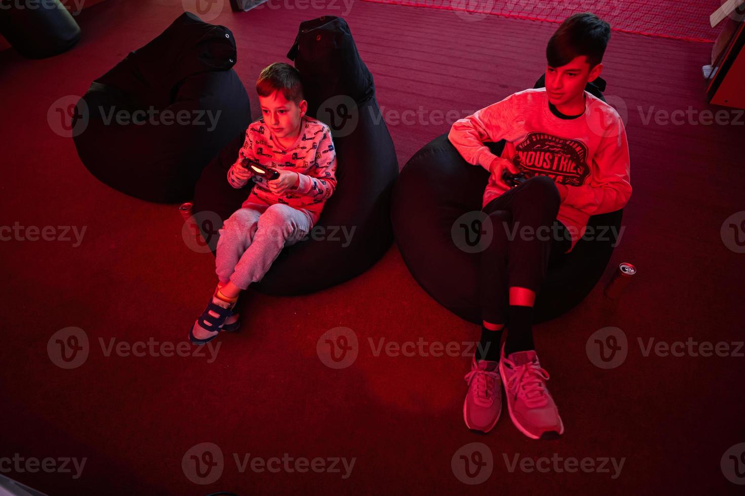 dos Niños jugadores jugar gamepad vídeo juego consola en rojo juego de azar habitación. foto