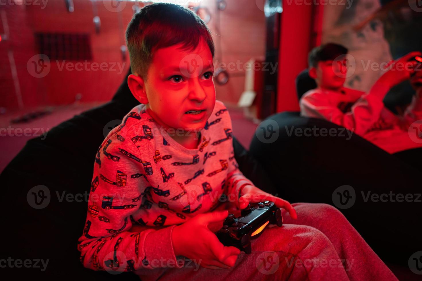 Two boys gamers play gamepad video game console in red gaming room. photo