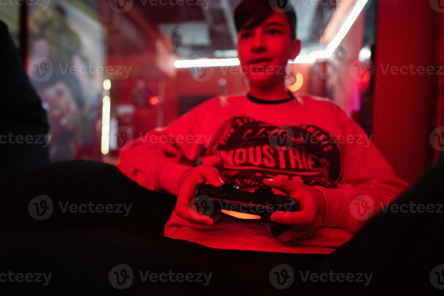 Teenager boy gamer play gamepad video game console in red gaming room. photo