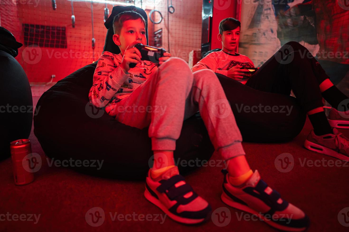 Two boys gamers play gamepad video game console in red gaming room. photo