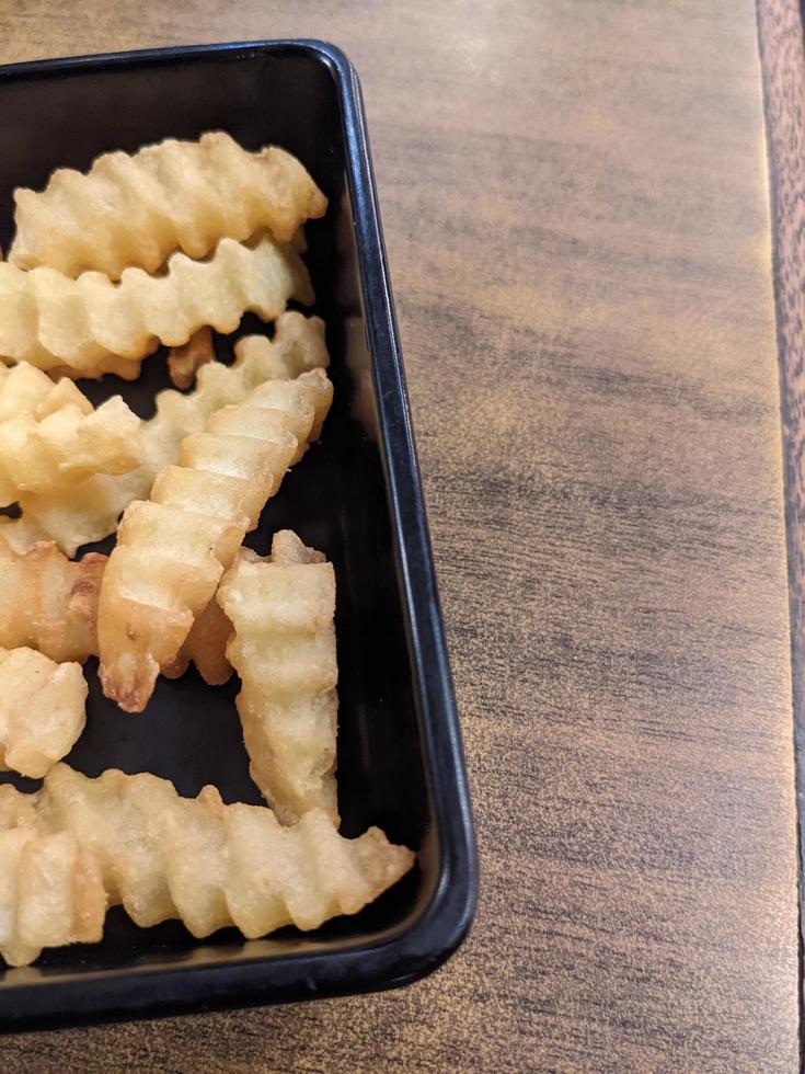 Close up fried fries with wooden table on the restaurant. The photo is suitable to use for traditional food background, poster and food content.