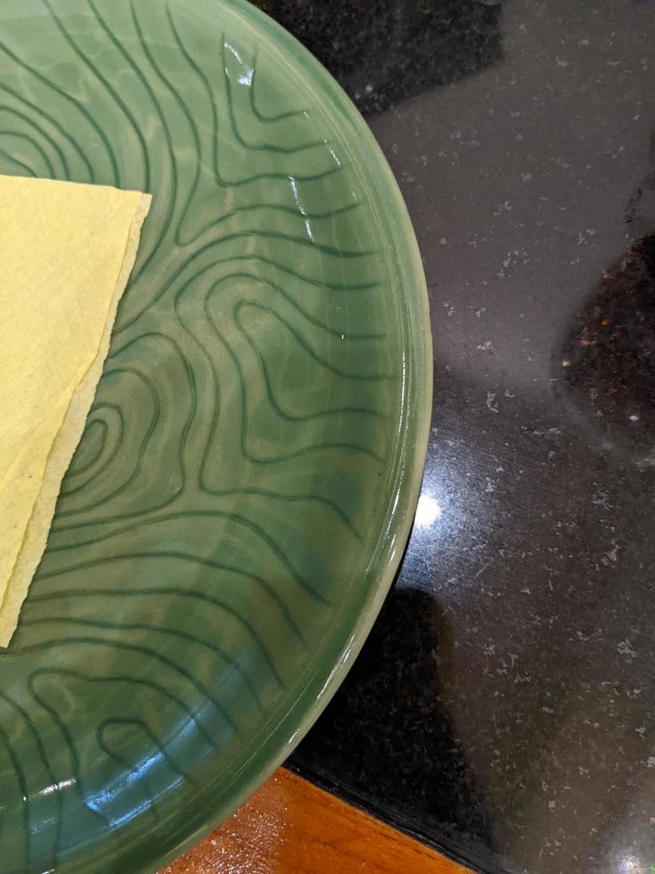 Empty green plate over the shiny table on the restaurant. The photo is suitable to use for restaurant background, menu poster and food content media.