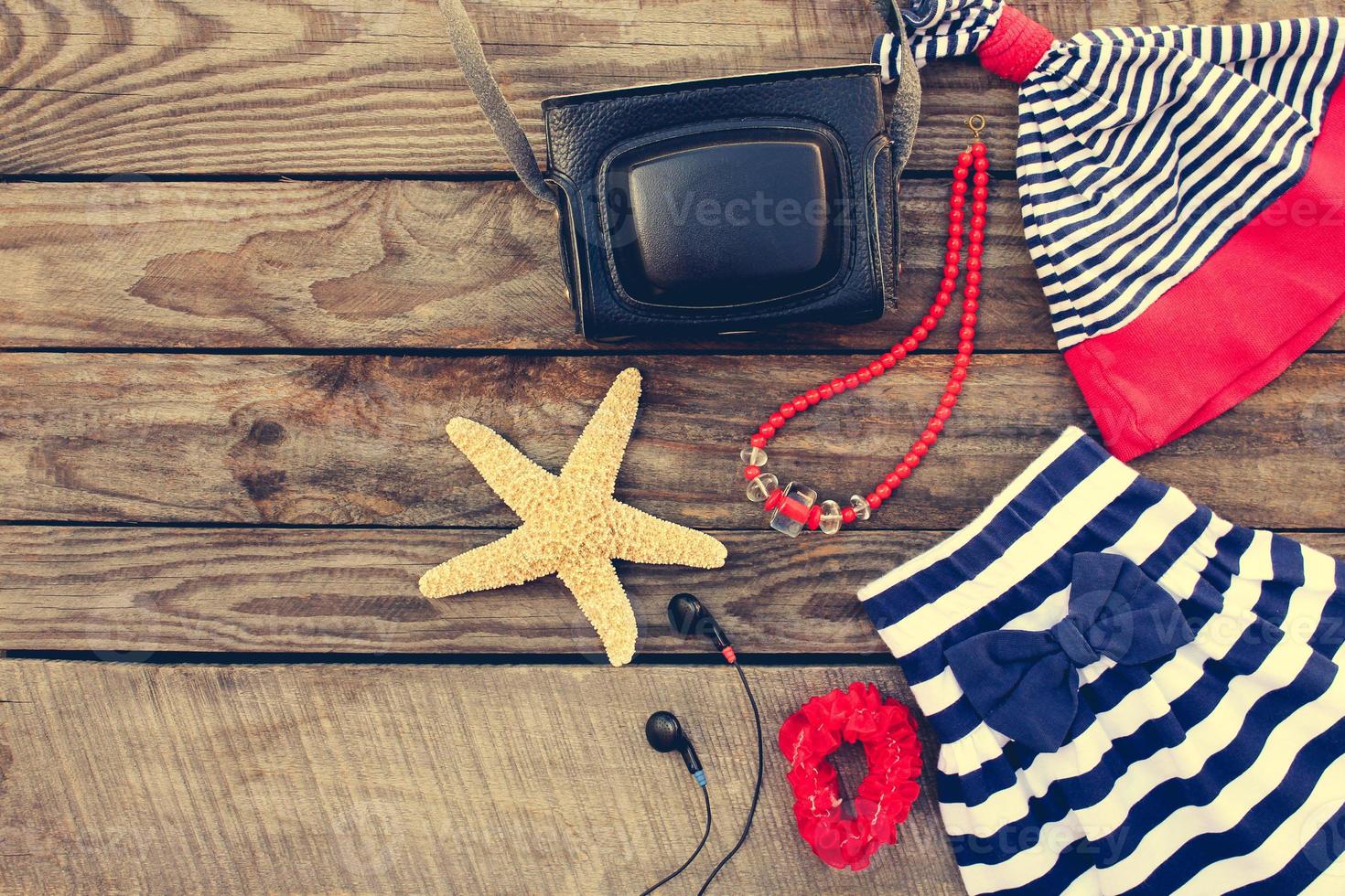 Summer children's clothing and beach accessories for your sea holiday on the old wooden background. Toned image. photo