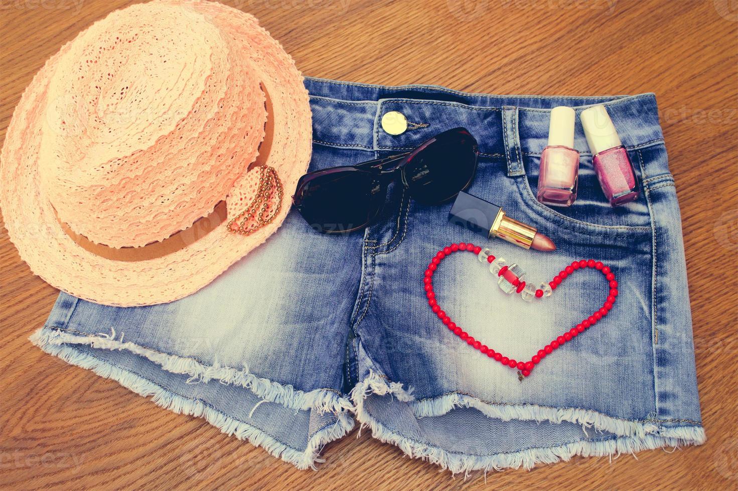 Summer women's accessories red sunglasses , beads, denim shorts, sun hat, nail polish, lipstick open. Toned image. photo