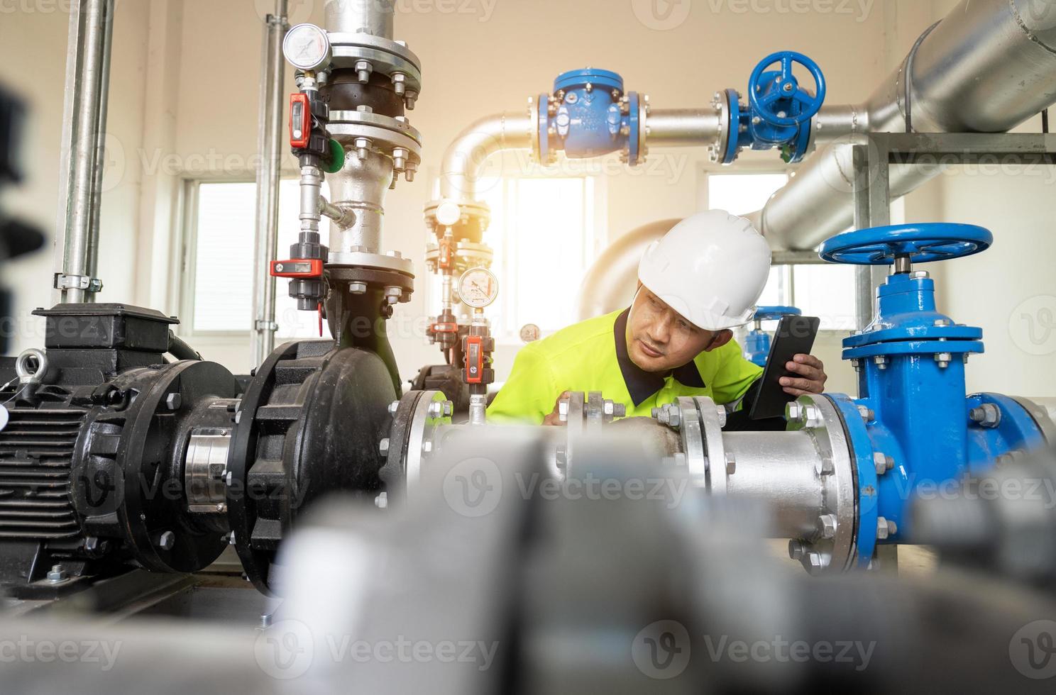 Asia oil and gas production control engineer or supervisor with digital pad monitoring natural gas supply and distribution in refinery Installation view of natural gas refinery pipes photo