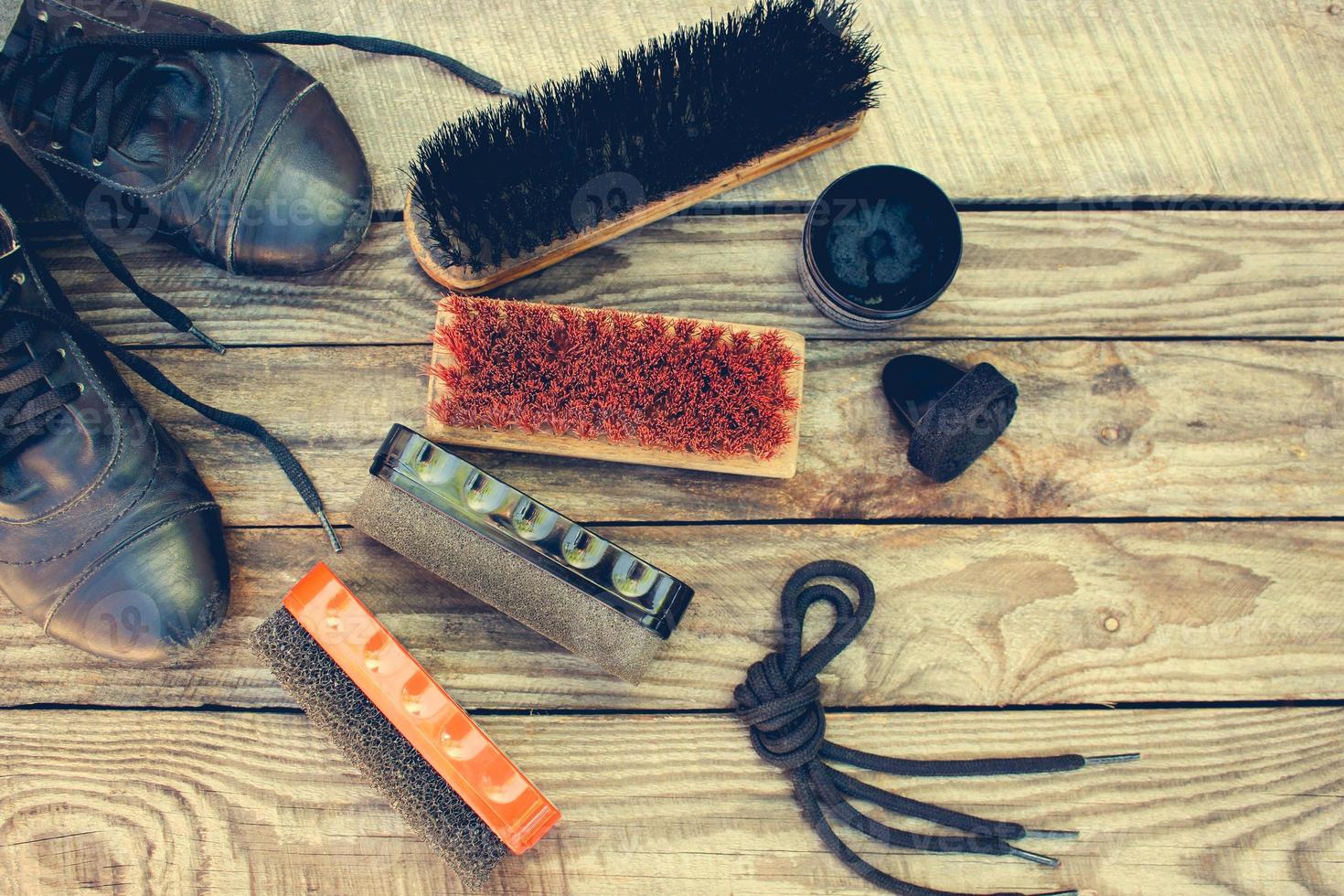 Shoes and care products for footwear on wooden background. Toned image. Top view. photo
