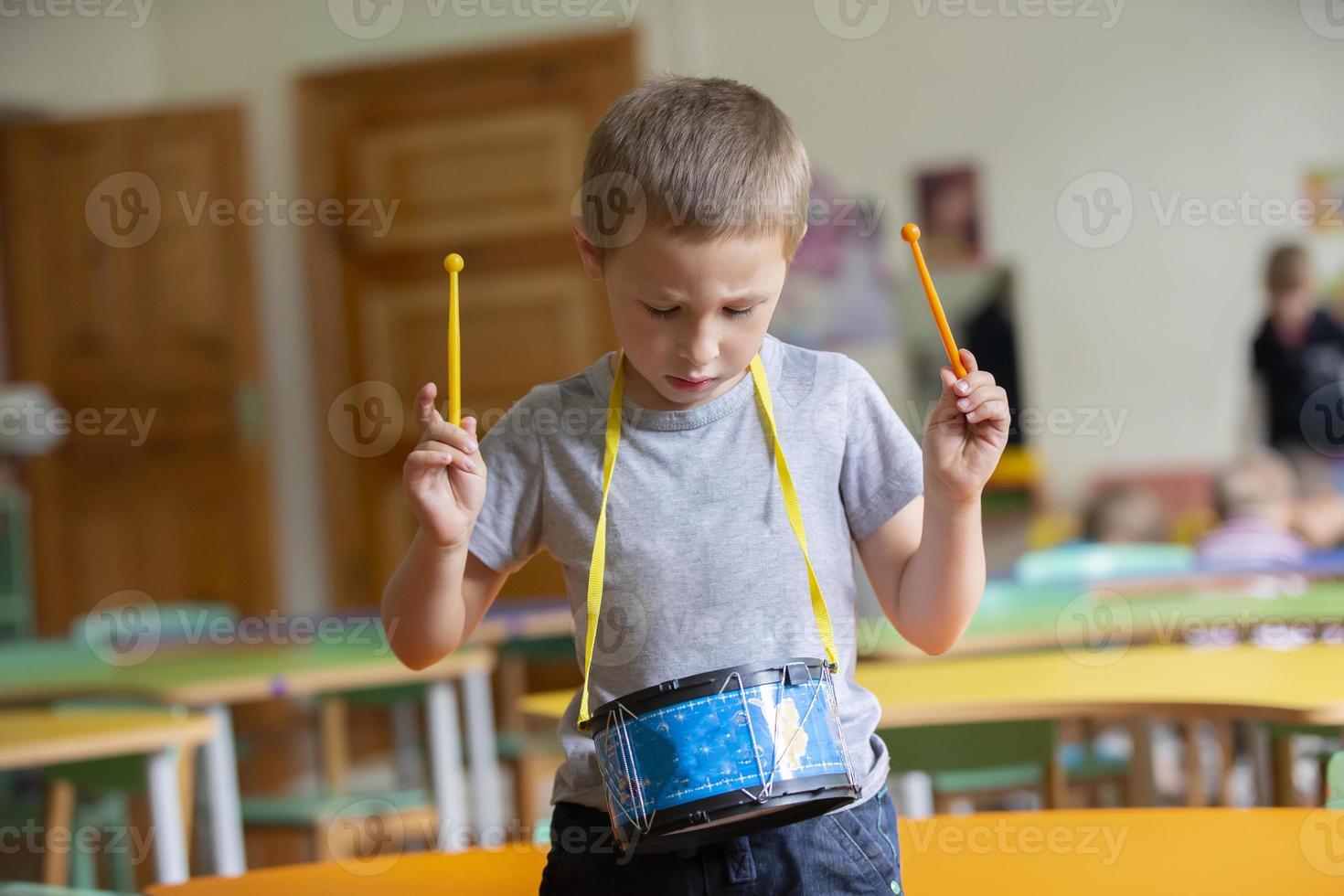 pequeño chico obras de teatro un juguete tambor. talentoso chico futuro músico foto